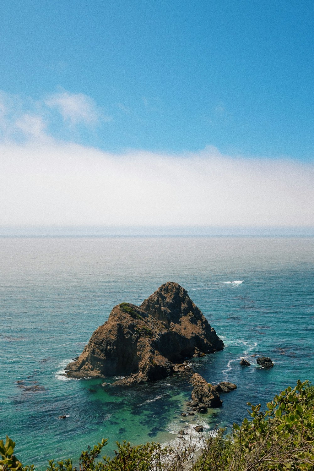 brown rock formation on sea under blue sky during daytime