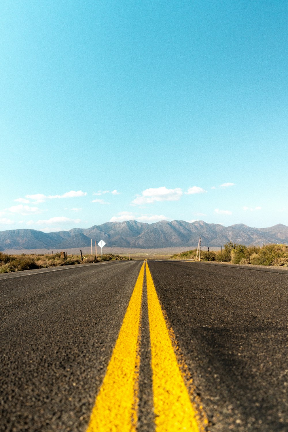 gray asphalt road near green grass field and mountains during daytime