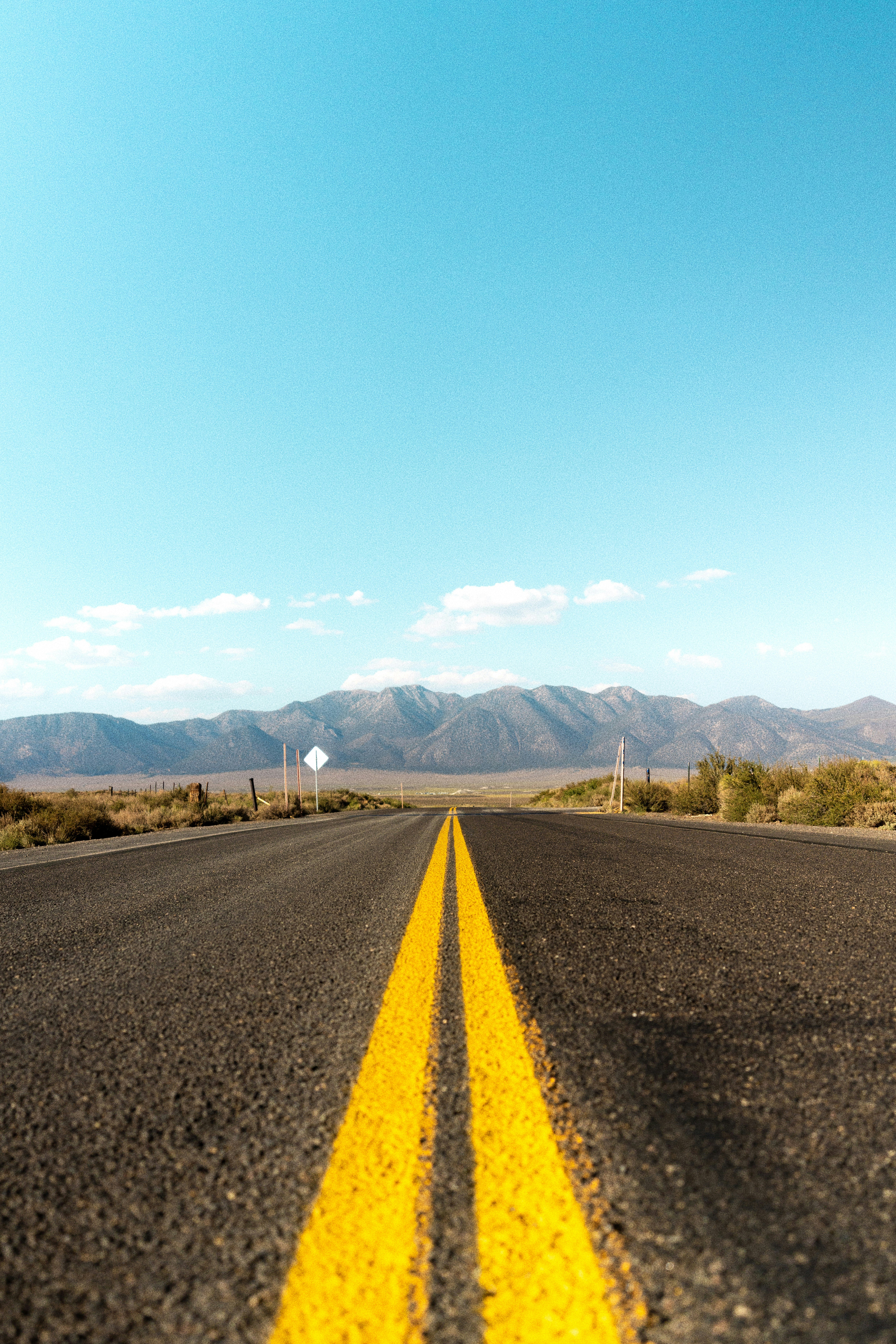 gray asphalt road near green grass field and mountains during daytime