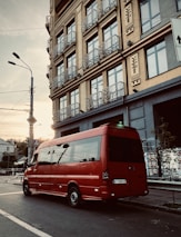 A delivery van parked outside a modern office building during sunrise.