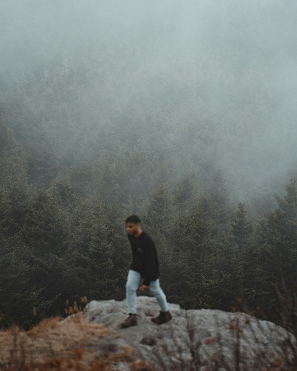 man in black shirt sitting on rock