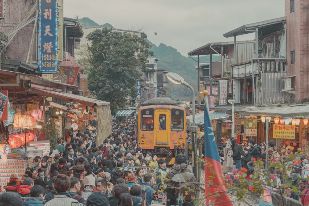 people standing on street near yellow train during daytime