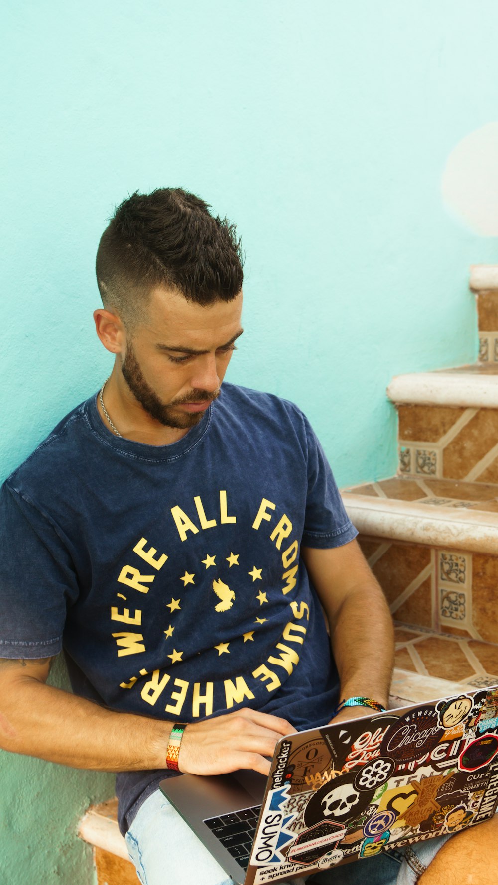 man in blue crew neck t-shirt sitting on brown wooden chair