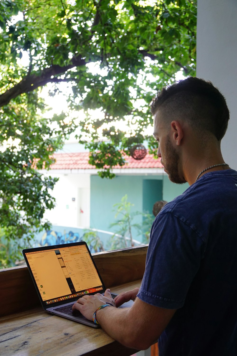 man in blue crew neck shirt sitting on brown wooden bench during daytime