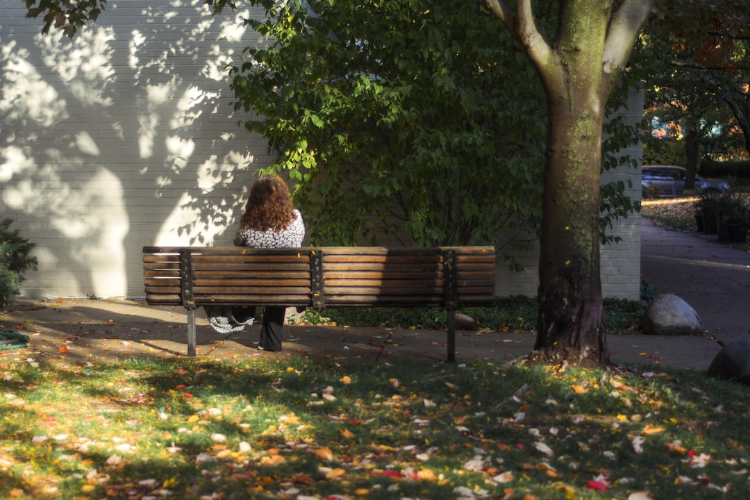 woman sitting on brown wooden bench during daytime