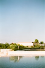 A serene villa exterior blending sleek modern architecture with lush green surroundings under a clear blue sky.