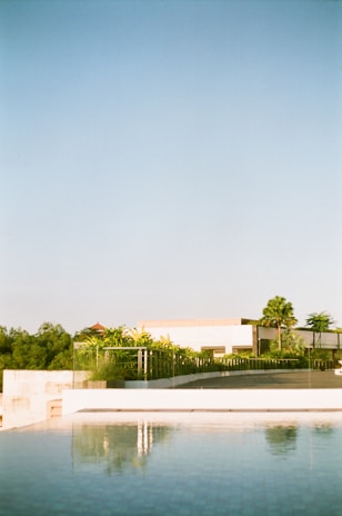 A serene view of a modern residential building surrounded by lush greenery and a clear blue sky.