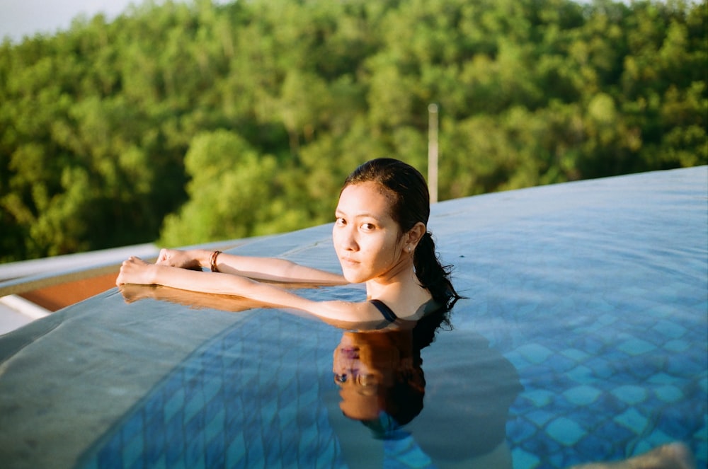 woman in blue and black tank top on swimming pool during daytime