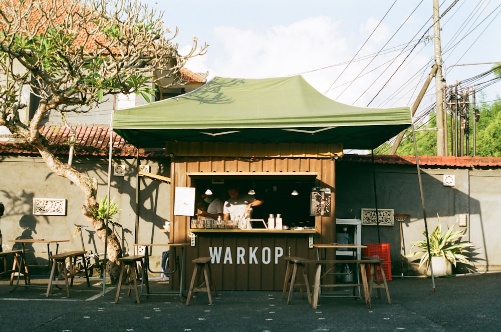 people sitting on brown wooden chairs near green and brown wooden house during daytime