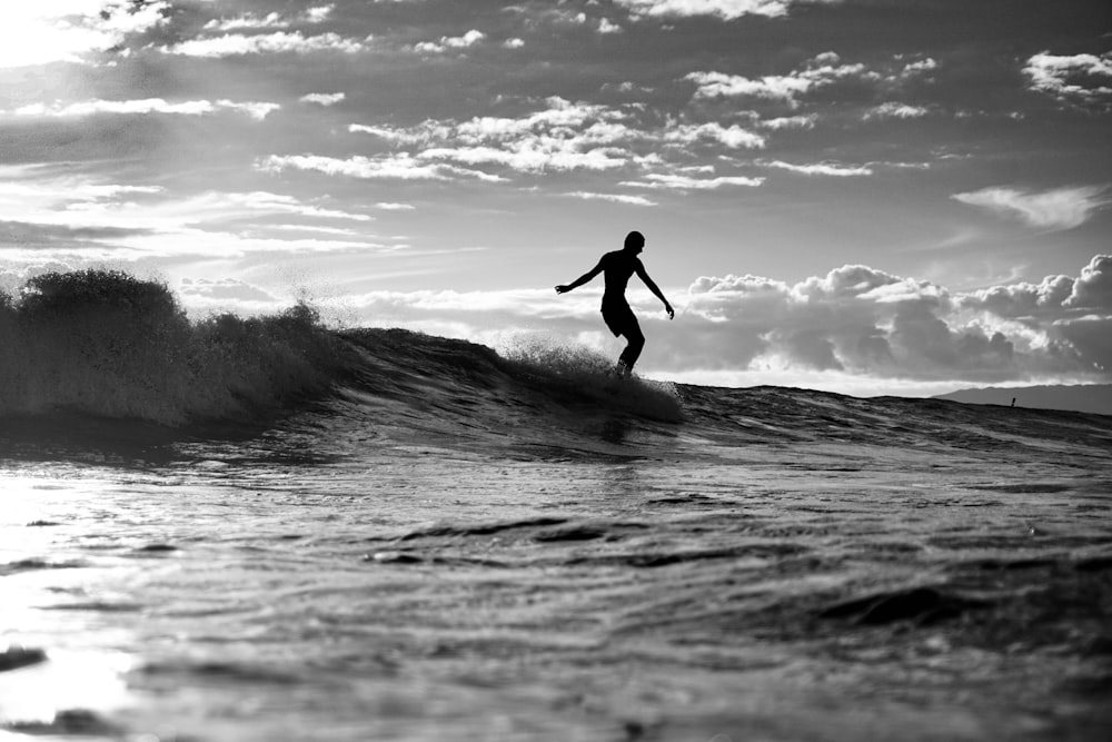 grayscale photo of man surfing on sea waves