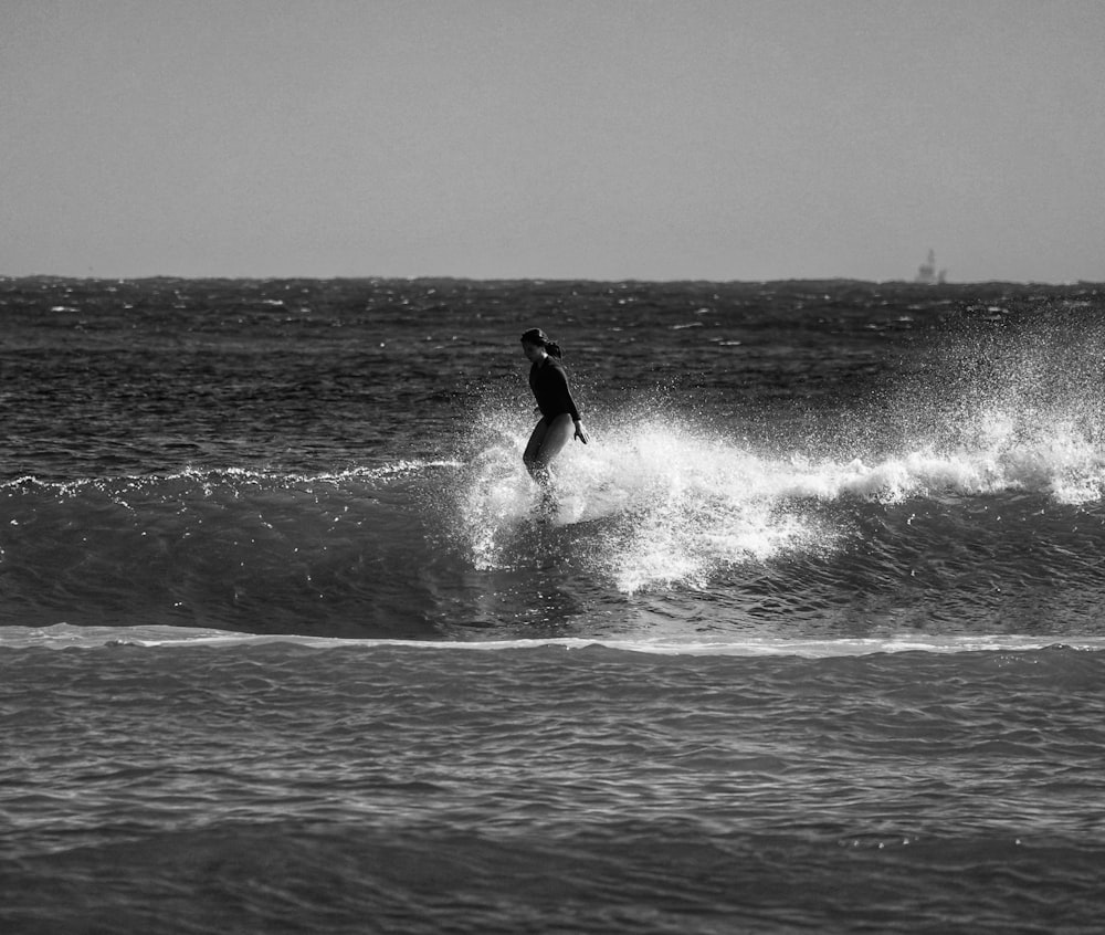 grayscale photo of man surfing on sea waves