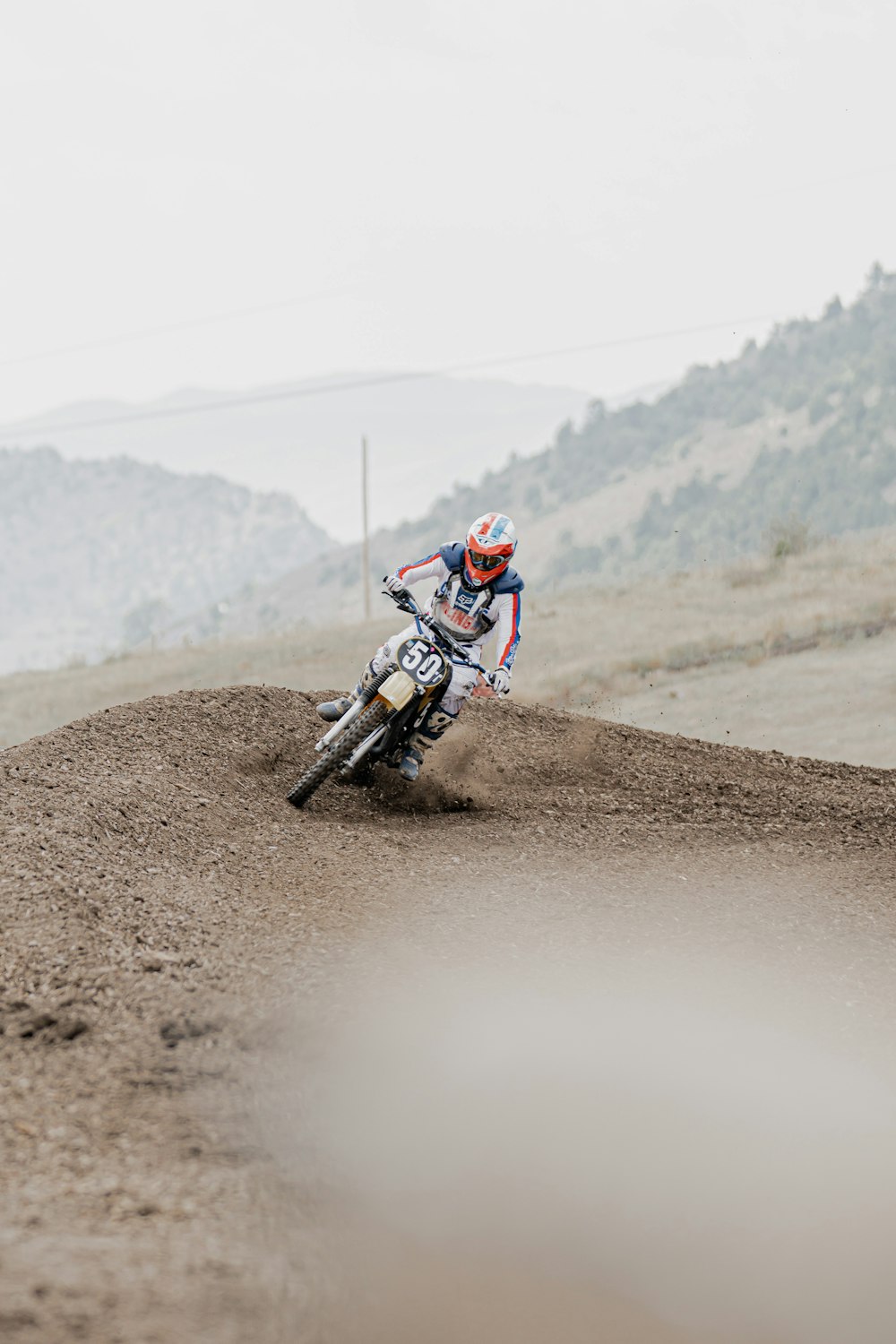 man in red and white helmet riding motocross dirt bike on brown dirt road during daytime