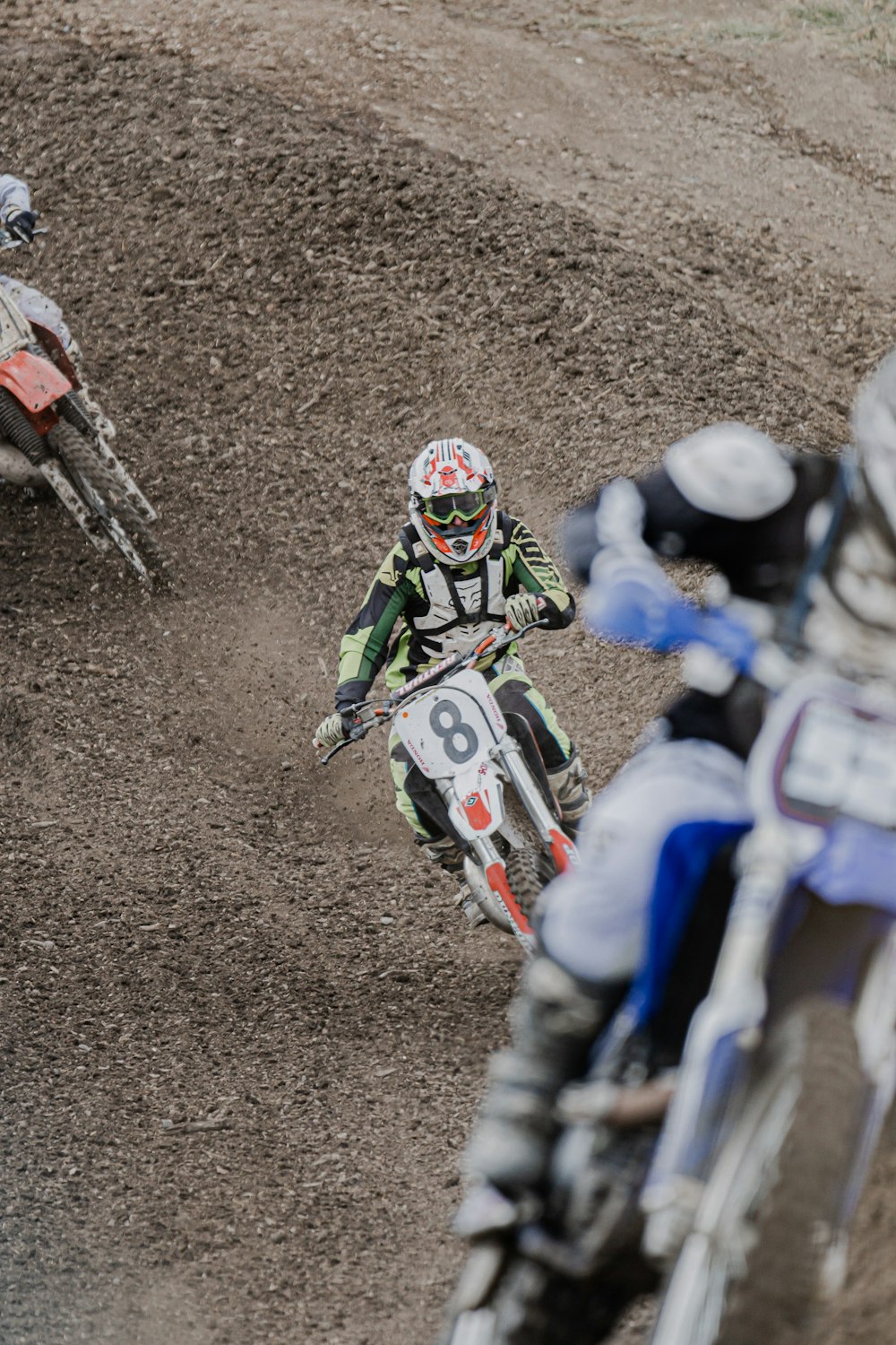 man in white and green motorcycle suit riding motocross dirt bike