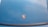 A car hood is painted in a blue color with a Porsche logo prominently displayed in the center.