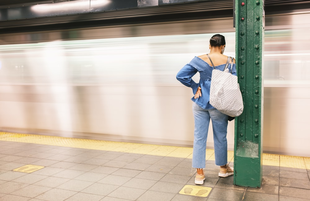 woman in blue denim jacket and white pants standing on white floor tiles