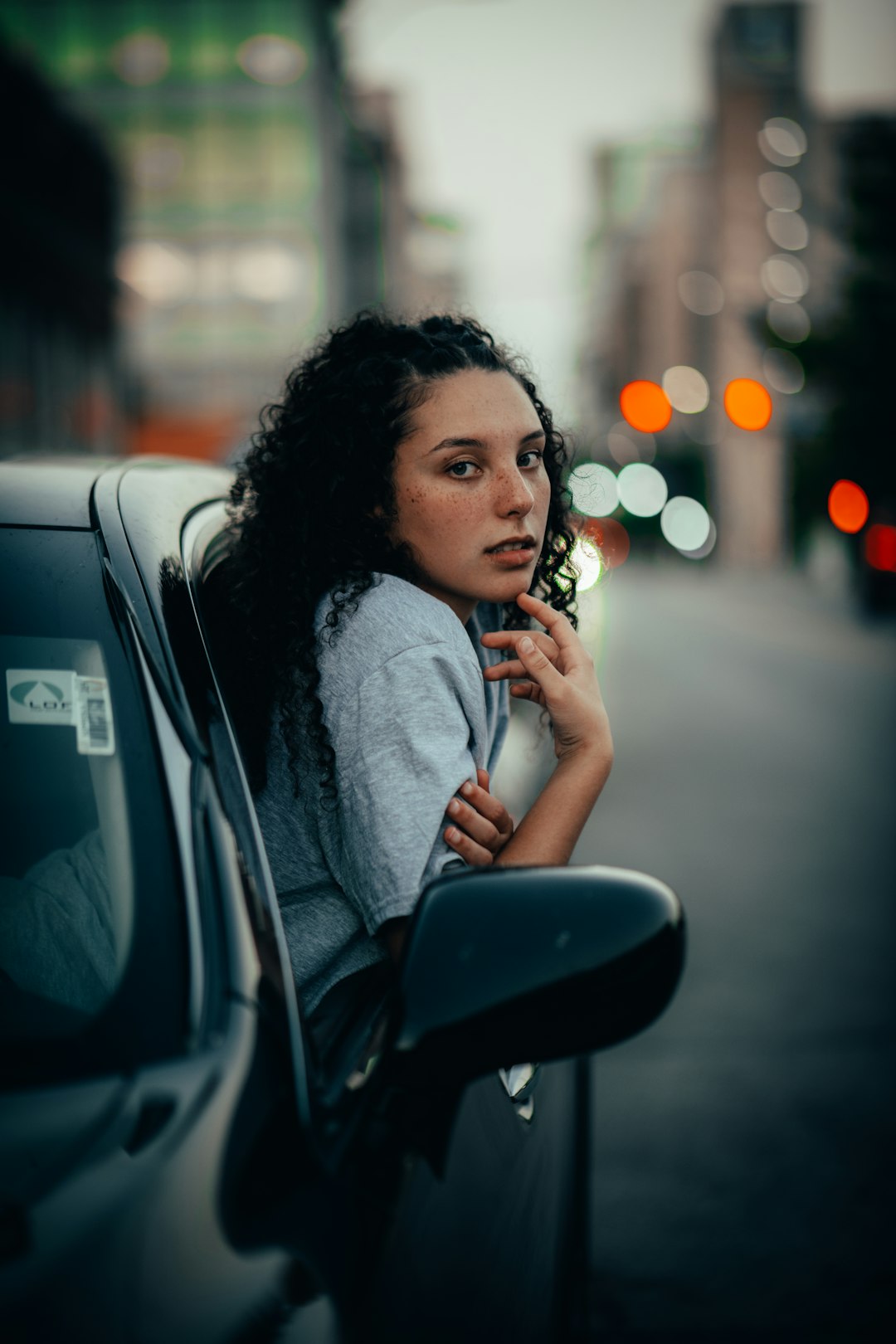 woman in gray sweater sitting on black car