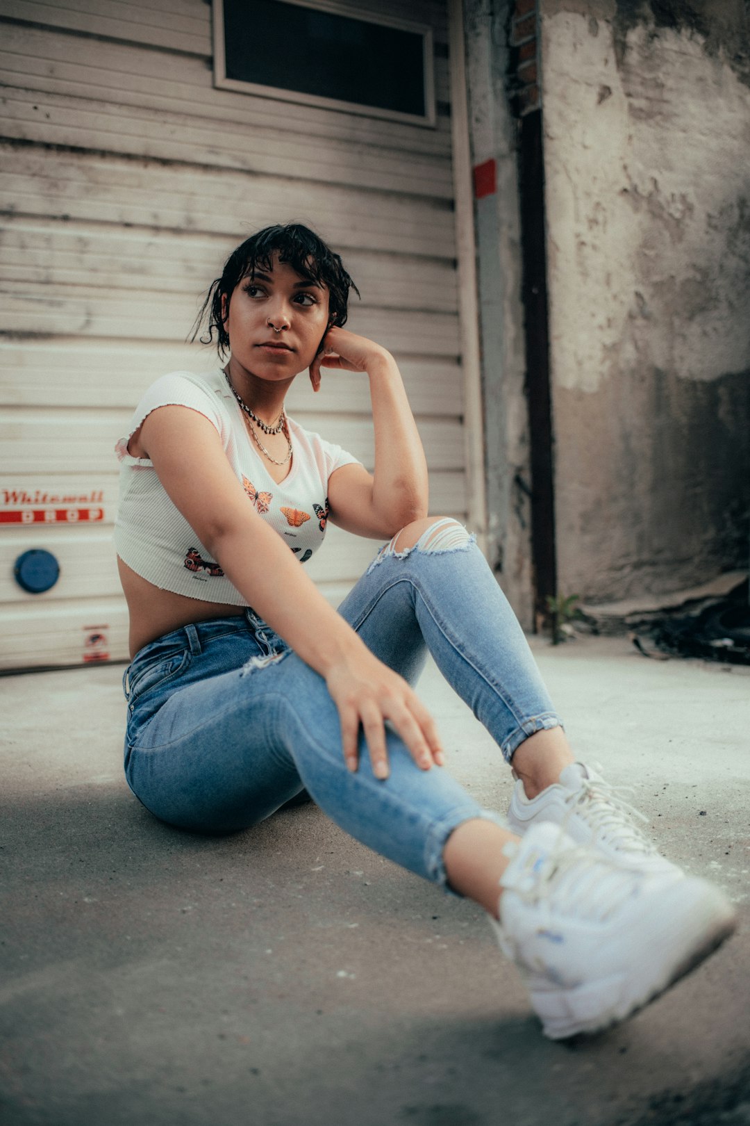 woman in white shirt and blue denim jeans sitting on floor