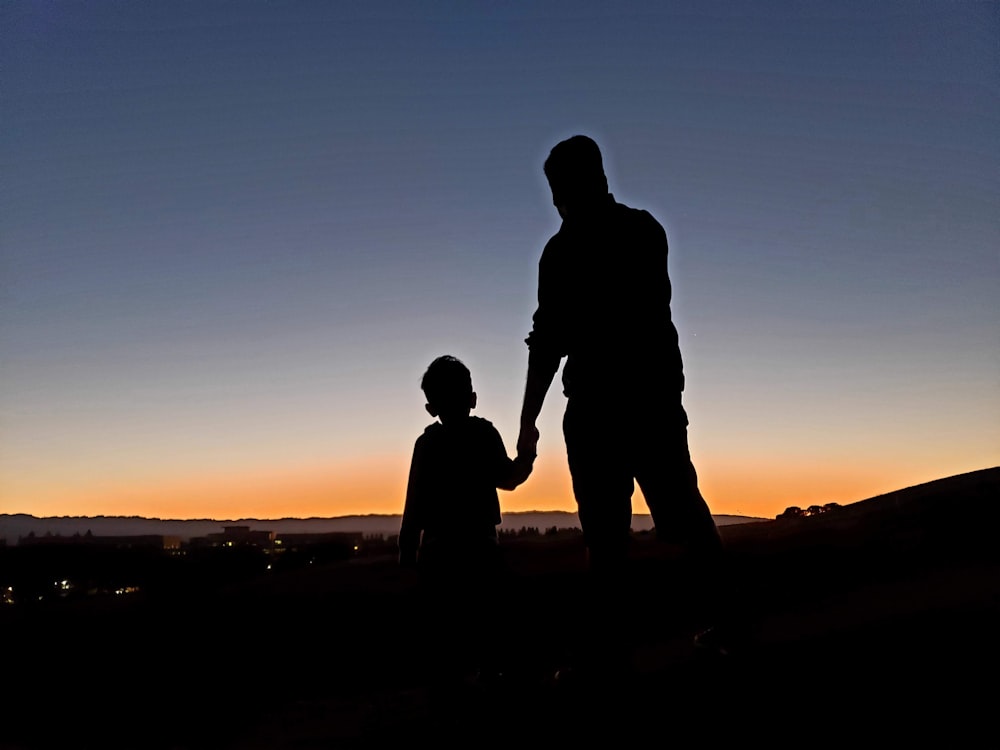 silhouette of man and woman standing on beach during sunset