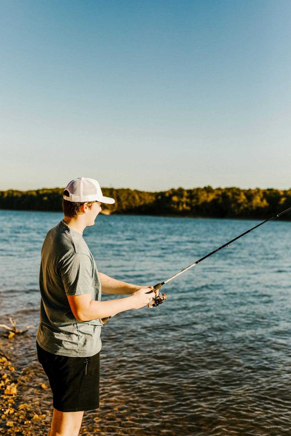 man in grey t-shirt fishing on lake during daytime