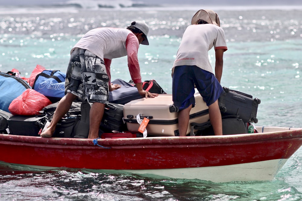 Hombre con camisa gris y pantalones cortos azules sentado en un barco rojo y blanco durante el día