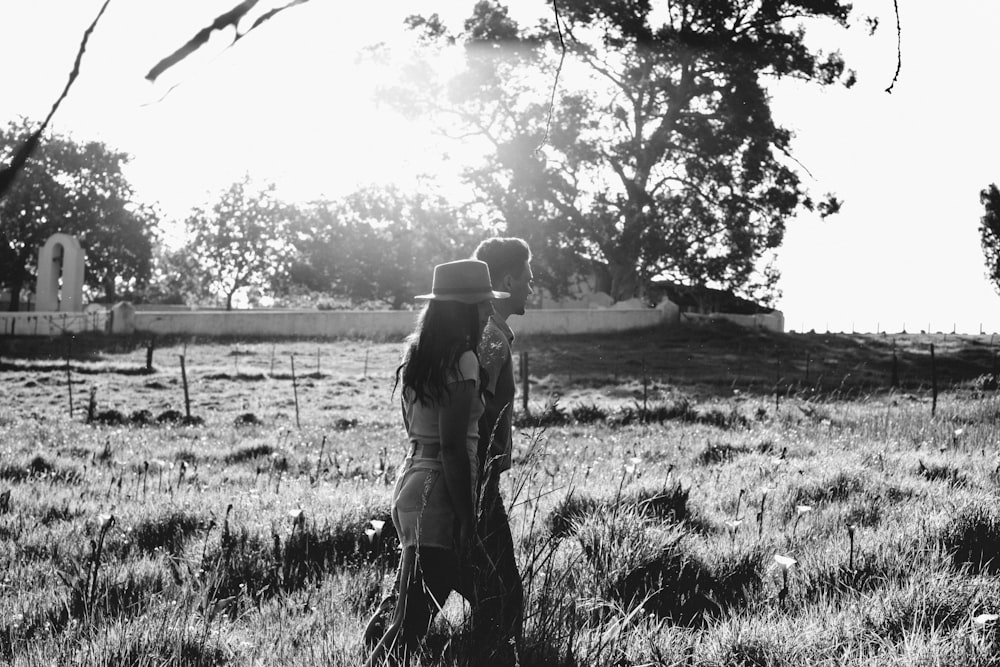 grayscale photo of woman in jacket and pants standing on grass field