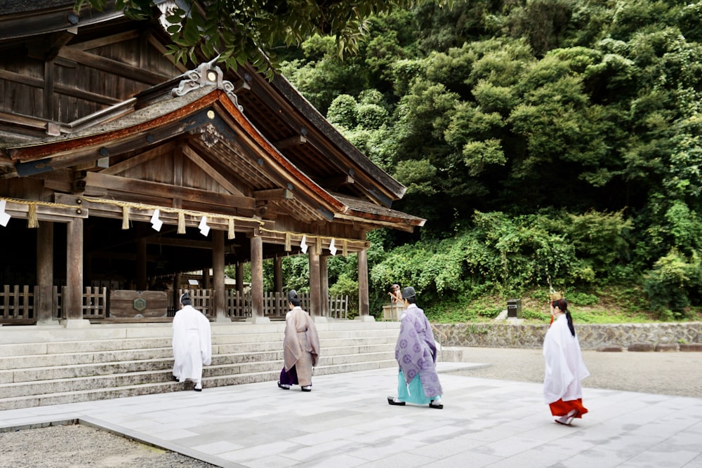woman in white dress walking on pathway near brown wooden temple during daytime