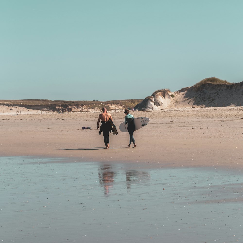 man and woman walking on beach during daytime