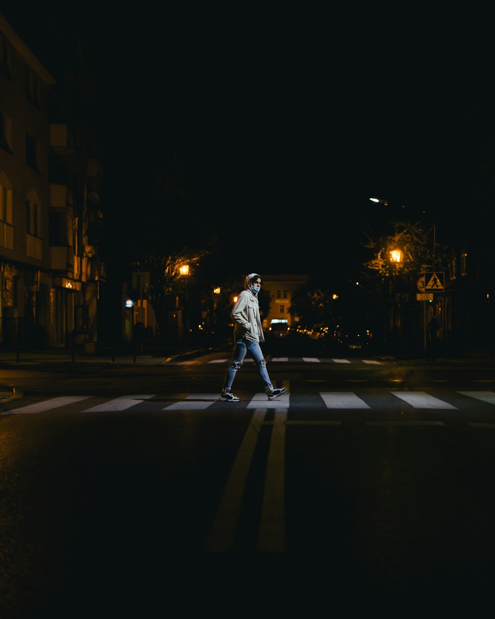 man in white t-shirt and white pants walking on street during night time