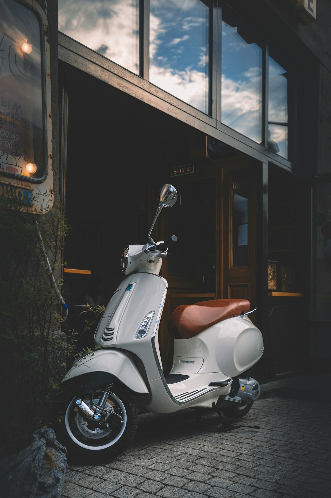 white motor scooter parked beside building during night time