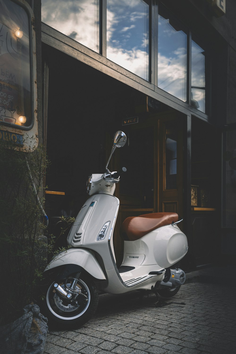 white motor scooter parked beside building during night time