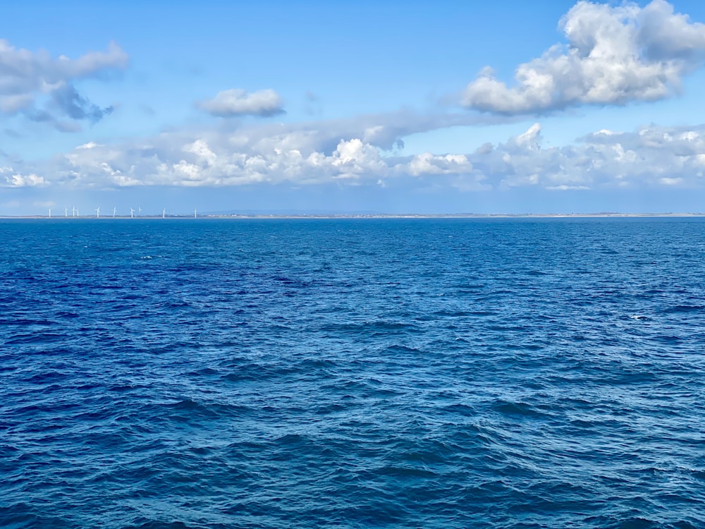 Mer bleue sous ciel bleu et nuages blancs pendant la journée