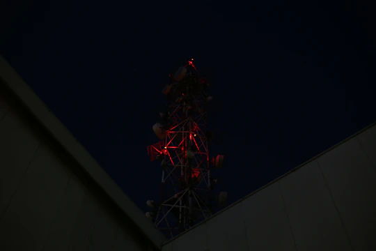A sleek black and red telecommunications tower glowing at dusk.