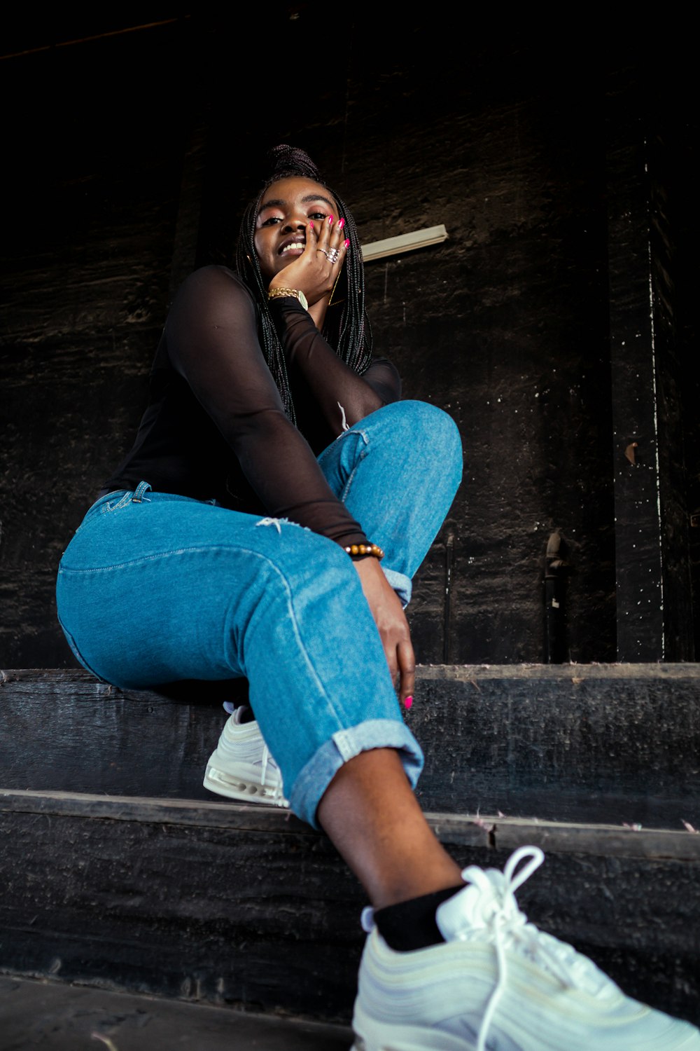 woman in black shirt and blue denim jeans sitting on wooden floor