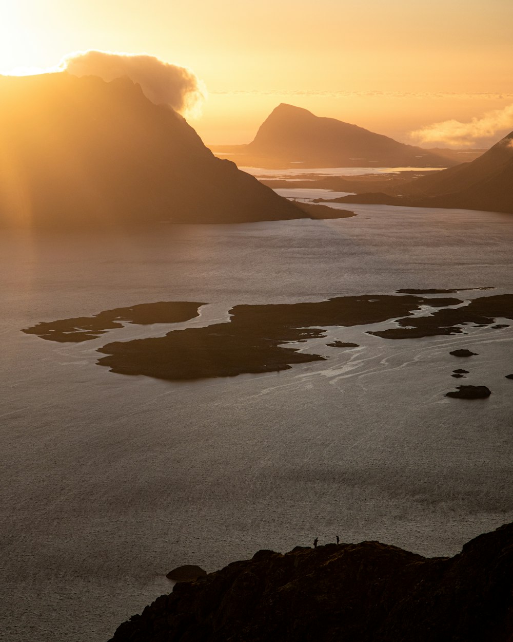 silhouette of mountain near body of water during sunset