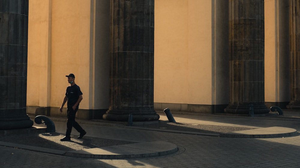 man in black jacket walking on sidewalk during daytime