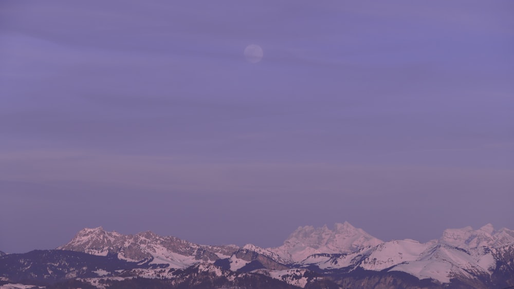 snow covered mountains under gray sky