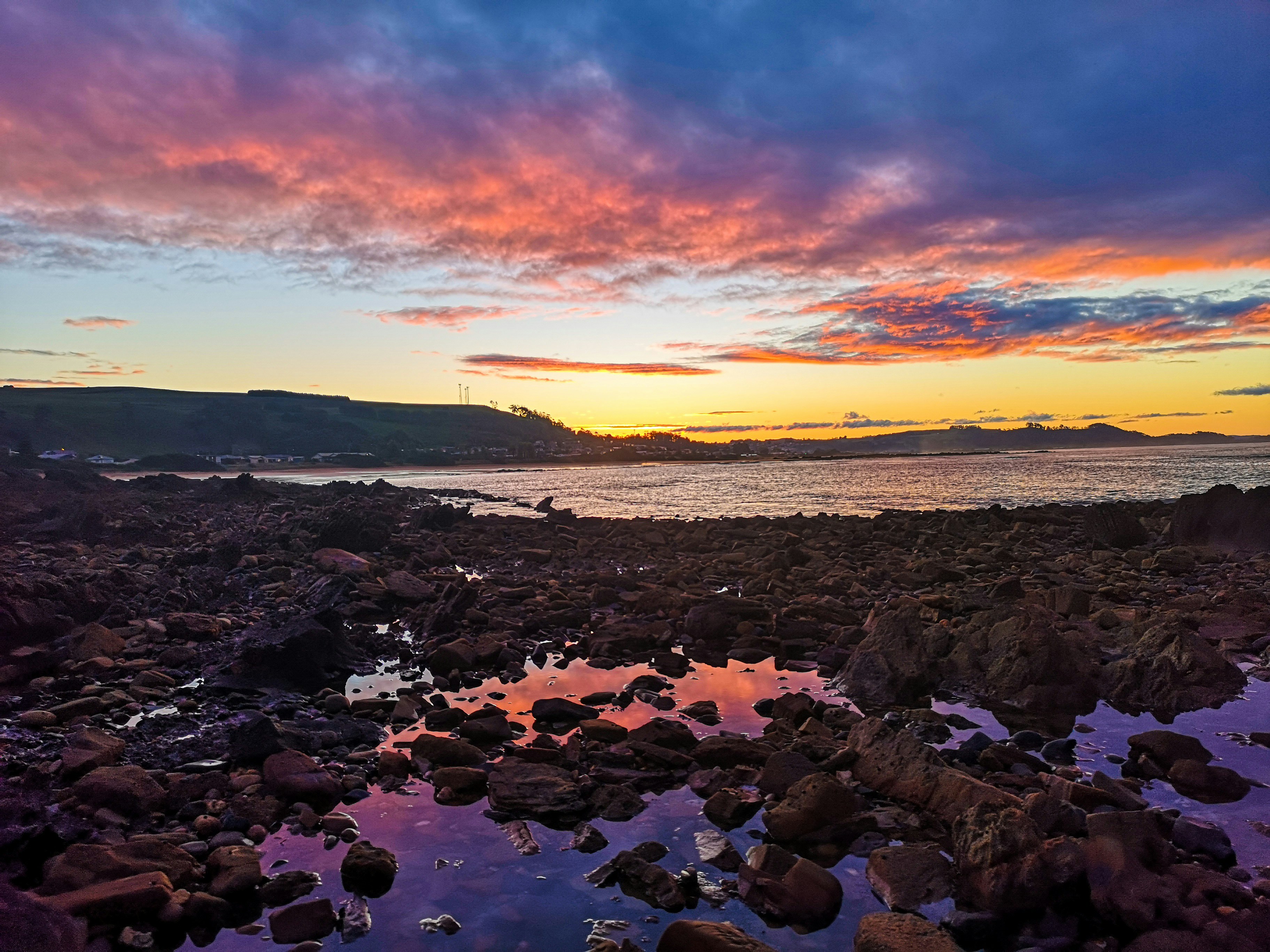 costa rocosa bajo el cielo naranja y azul