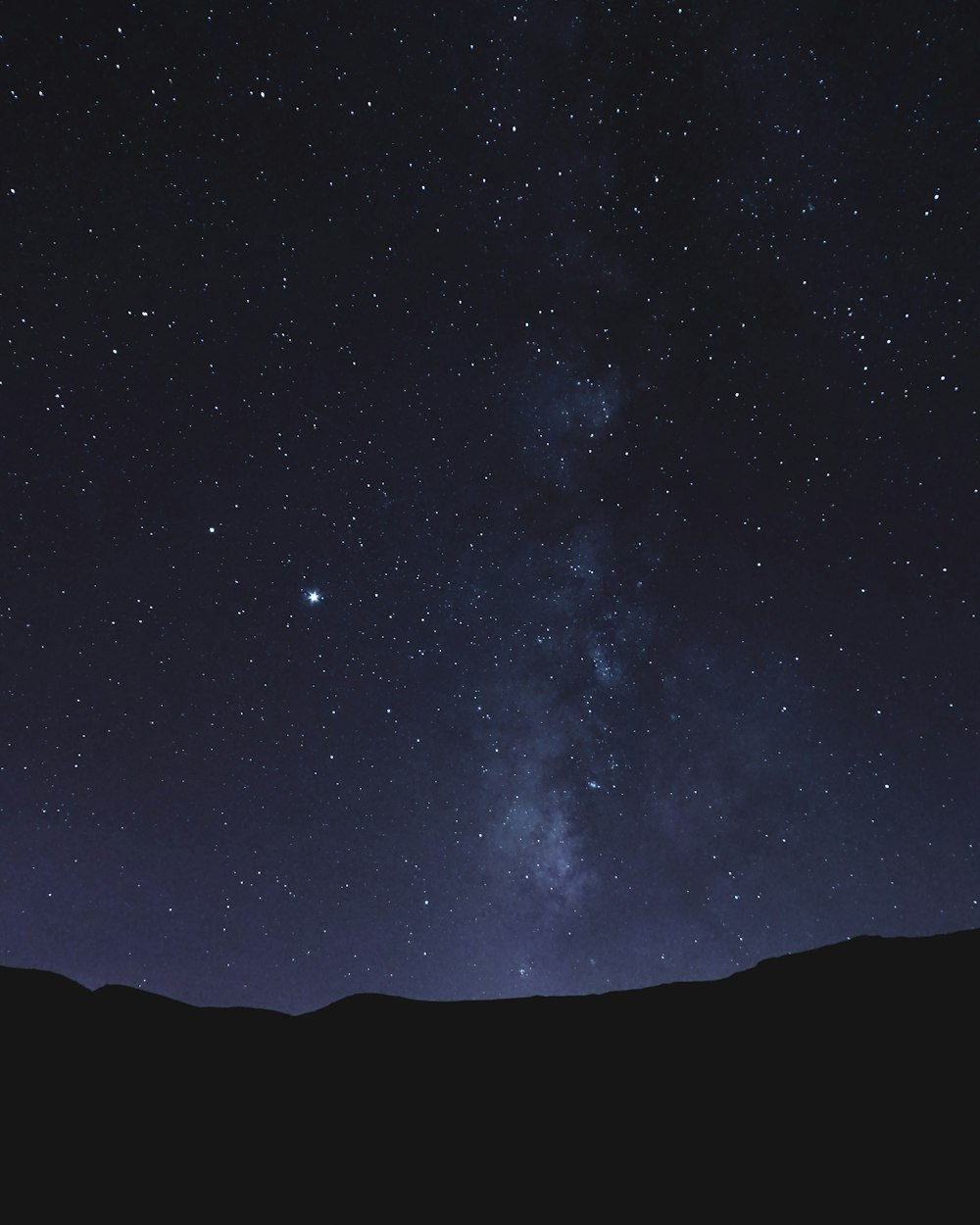 silhouette of mountain under starry night