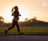 woman in black sports bra and black pants running on water during sunset