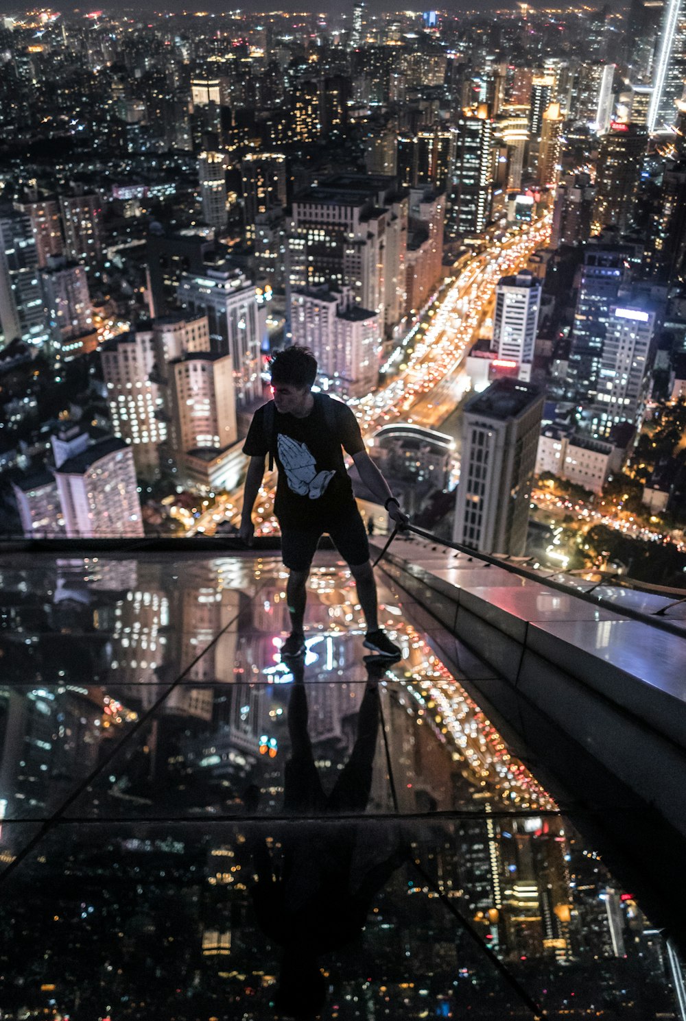 man in black t-shirt and blue denim jeans standing on top of building during night