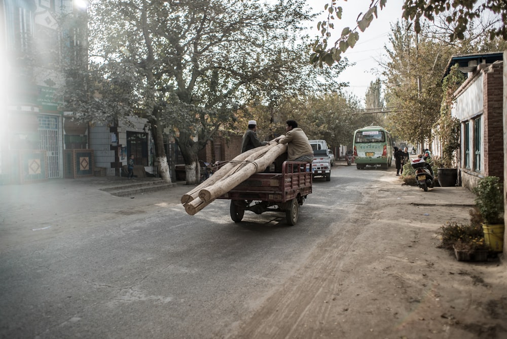 homme en chemise bleue assis sur un banc en bois brun pendant la journée