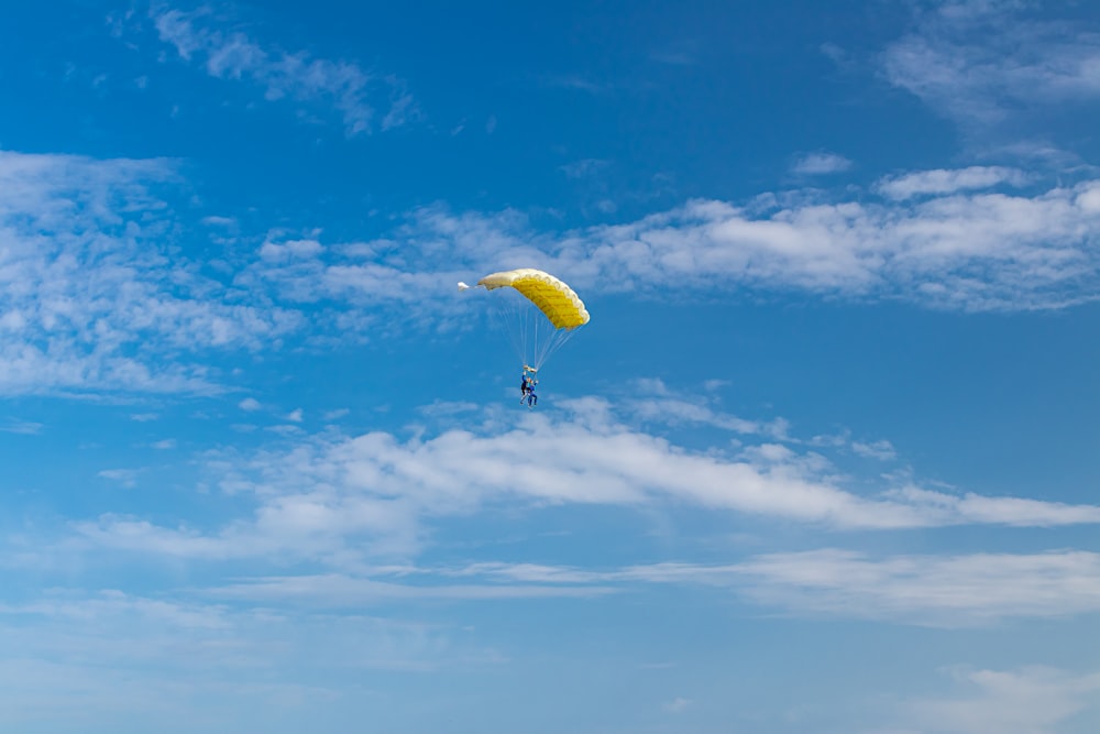 person in yellow parachute under blue sky during daytime