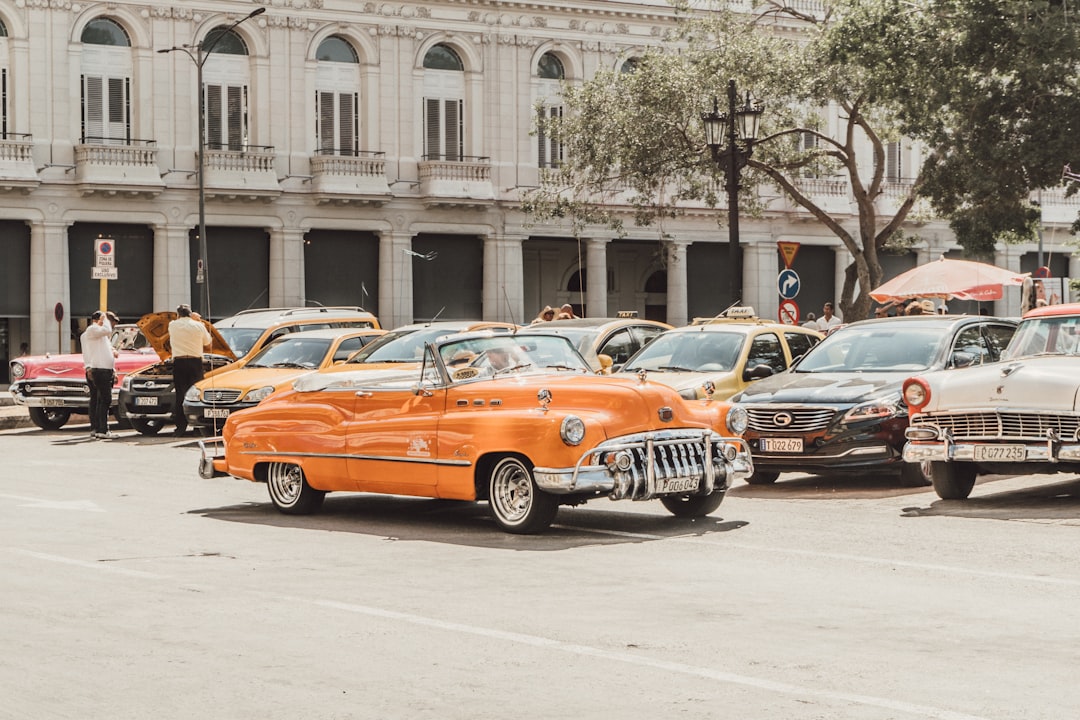 orange sedan parked near white concrete building during daytime