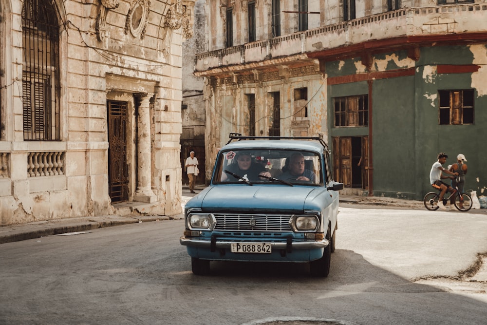 blue car parked beside brown concrete building during daytime