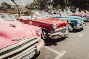 red and white vintage car parked on gray asphalt road during daytime