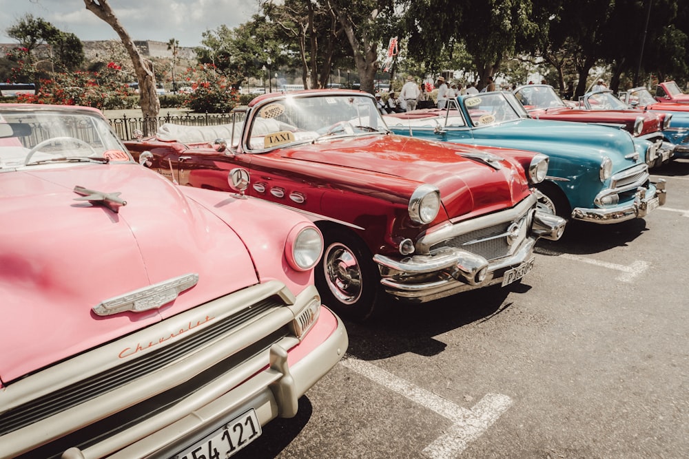 red and white vintage car parked on gray asphalt road during daytime