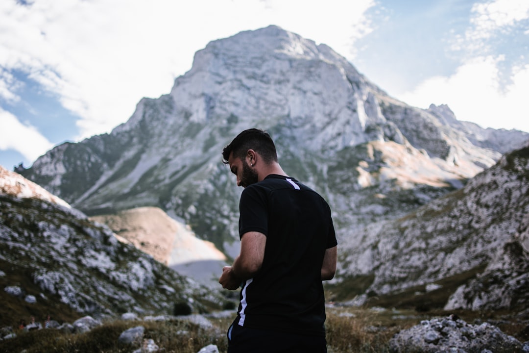 man in black t-shirt standing on rocky mountain during daytime