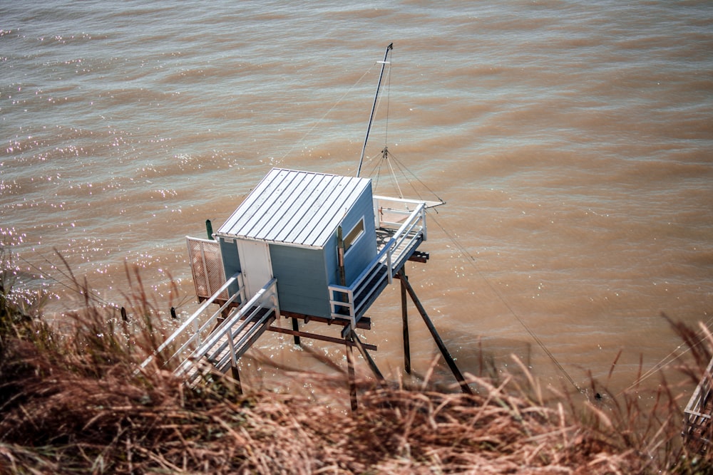 blue and white wooden house on brown sand near body of water during daytime