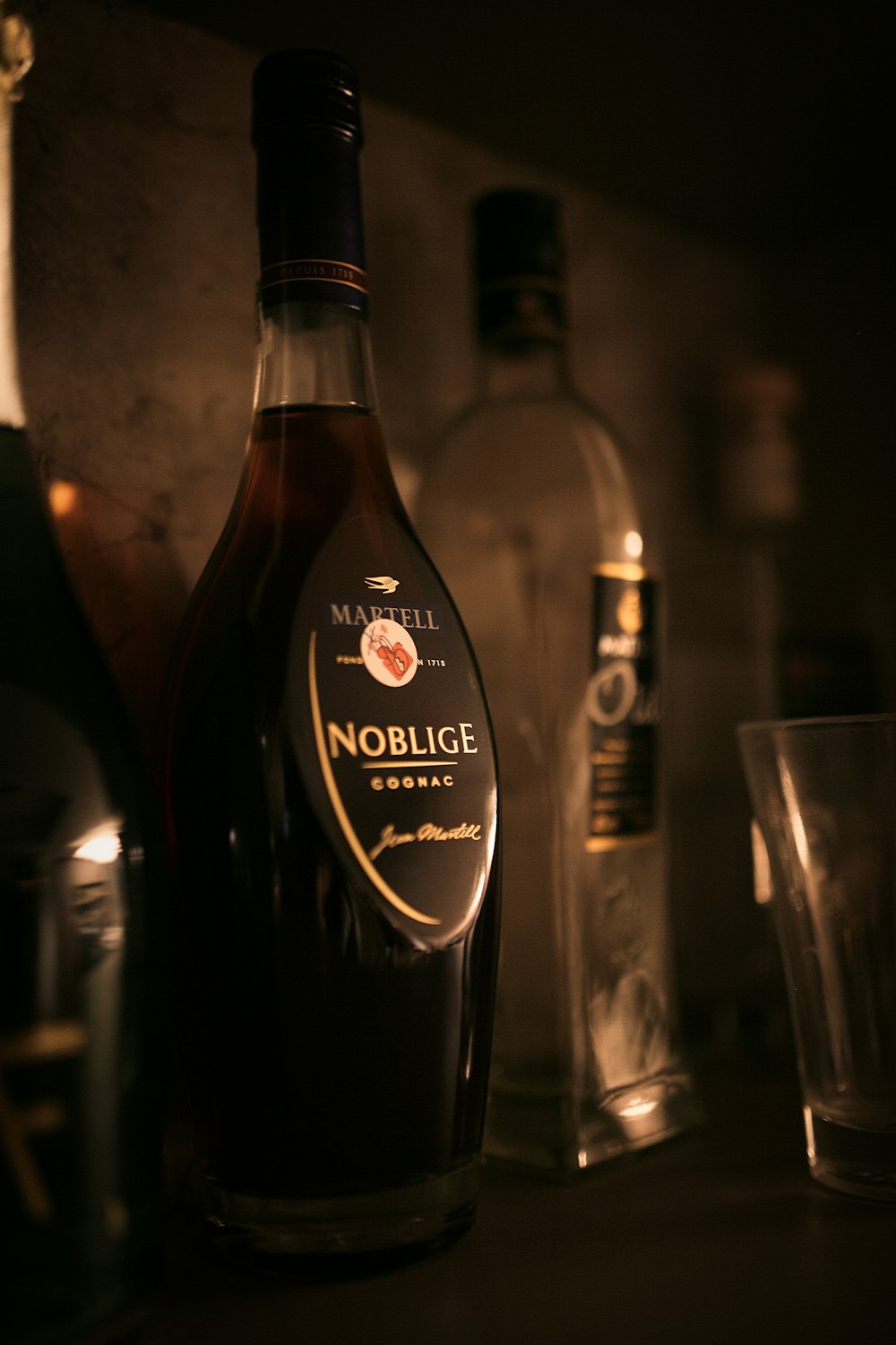 black wine bottle beside clear drinking glass