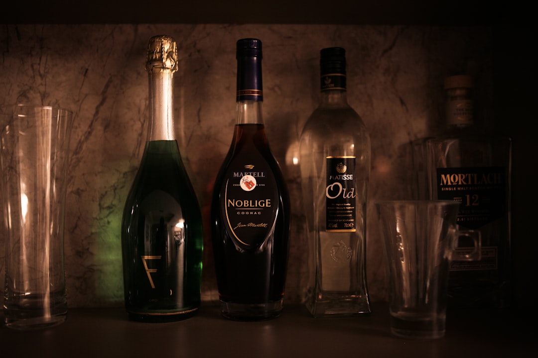 black glass bottle beside clear drinking glass